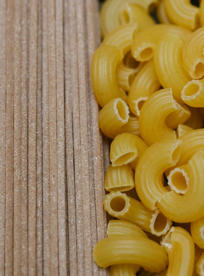 a pile of pasta sitting on top of a wooden table, half image, detailed product image, cavities, a pair of ribbed