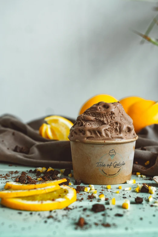 a cup of ice cream sitting on top of a table, studio ghibili, orange, tula, chocolate frosting