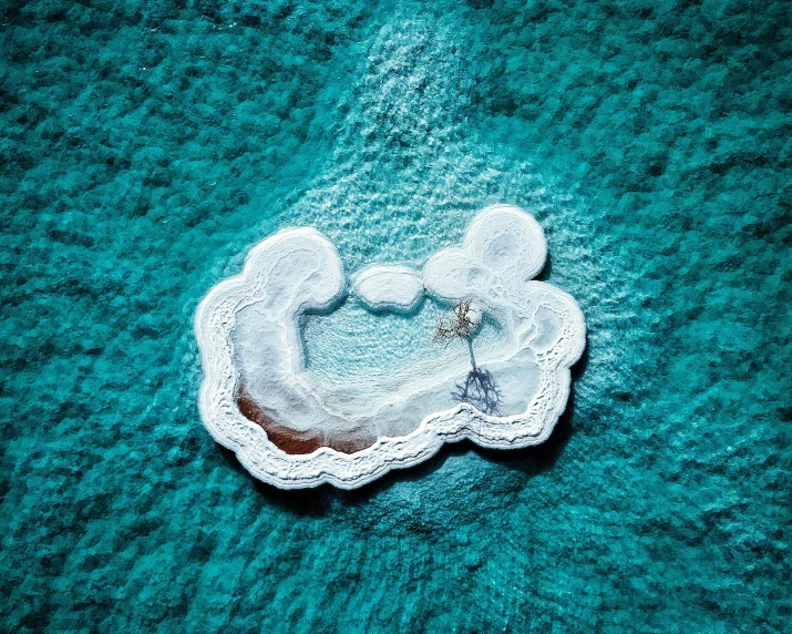 a white teddy bear sitting on top of a blue blanket, a microscopic photo, inspired by Scarlett Hooft Graafland, land art, very beautiful!! aerial shot, turquoise water, intricate image, two medium sized islands