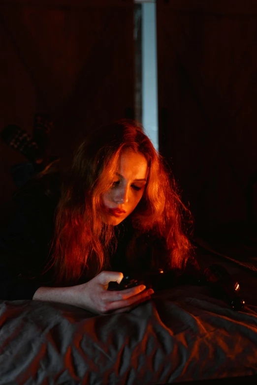 a woman laying in bed looking at her cell phone, inspired by Nan Goldin, pexels, digital art, orange skin and long fiery hair, female occultist, guitarist, walking down