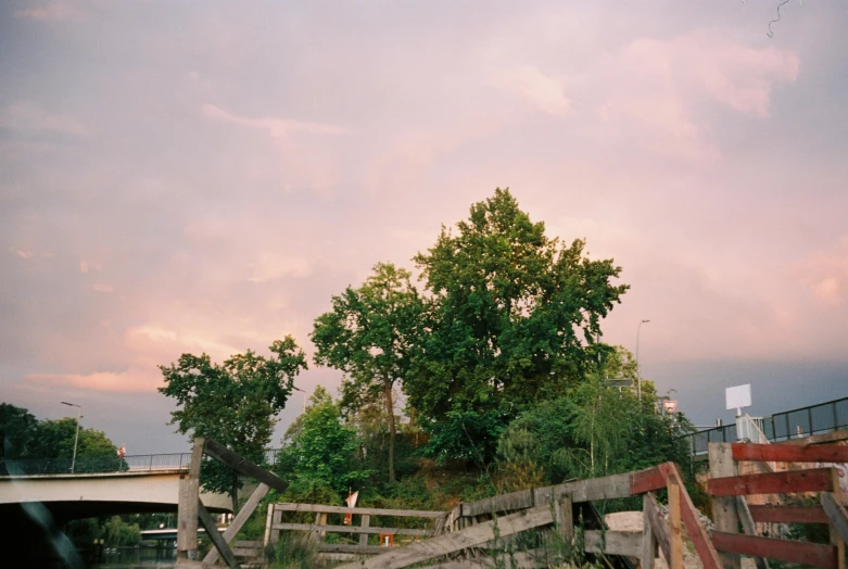 a man riding a skateboard up the side of a ramp, by Nathalie Rattner, strange trees and clouds, pink golden hour, joel meyerowitz, near a river