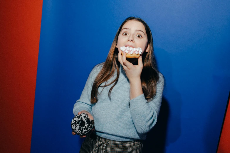 a woman holding a doughnut up to her mouth, an album cover, by Julia Pishtar, pexels contest winner, miranda cosgrove, cupcake, wearing a blue berries, elizabeth olsen