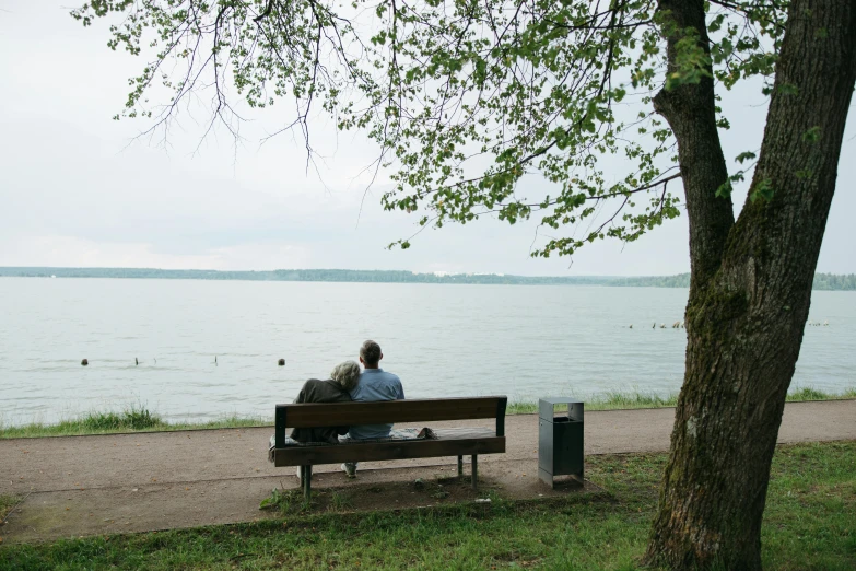 a man and a woman sitting on a bench by the water, from the distance, photo taken from far, behaelterverfolgung, taken on a 2010s camera