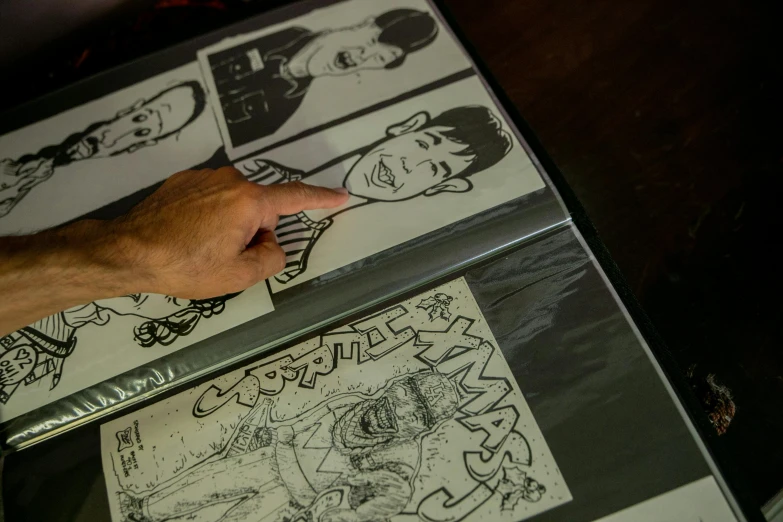 a person pointing to a comic book on a table, a cartoon, process art, local close up, engravings, portrait of jughead jones, thumbnail