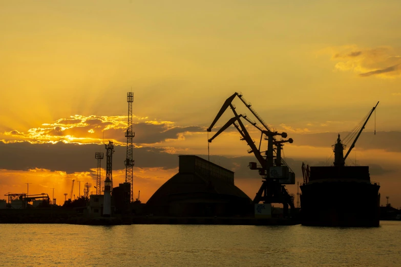 a couple of cranes sitting on top of a body of water, pexels contest winner, industrial apparent, low sun, ships, grain”