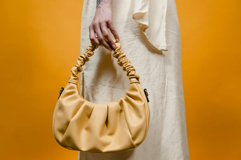 a woman in a white dress holding a beige purse, trending on pexels, bauhaus, colors: yellow, baggy, inflatable, golden collar