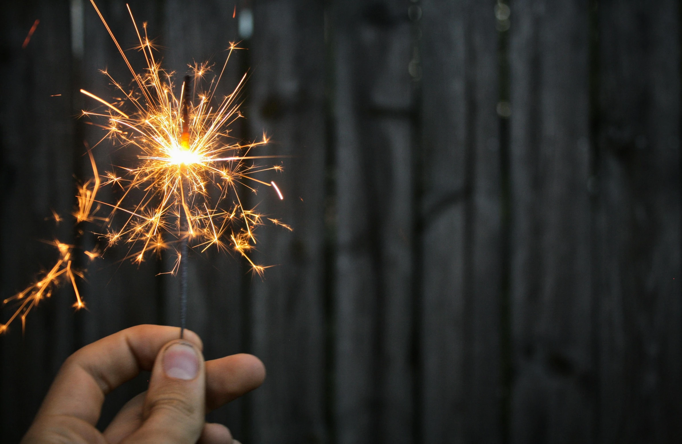 a person holding a sparkler in their hand, pexels contest winner, fourth of july, background image, midcentury modern, grey