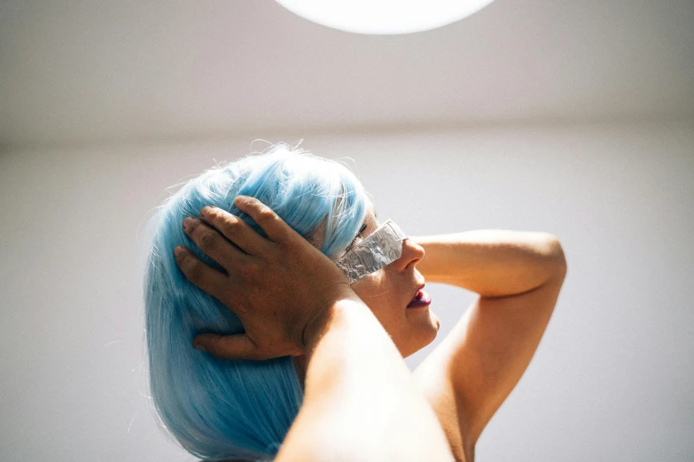 a woman with blue hair has her hands on her head, inspired by Elsa Bleda, trending on pexels, light and space, glamourous cosplay, slightly tanned, as she looks up at the ceiling, blue moon