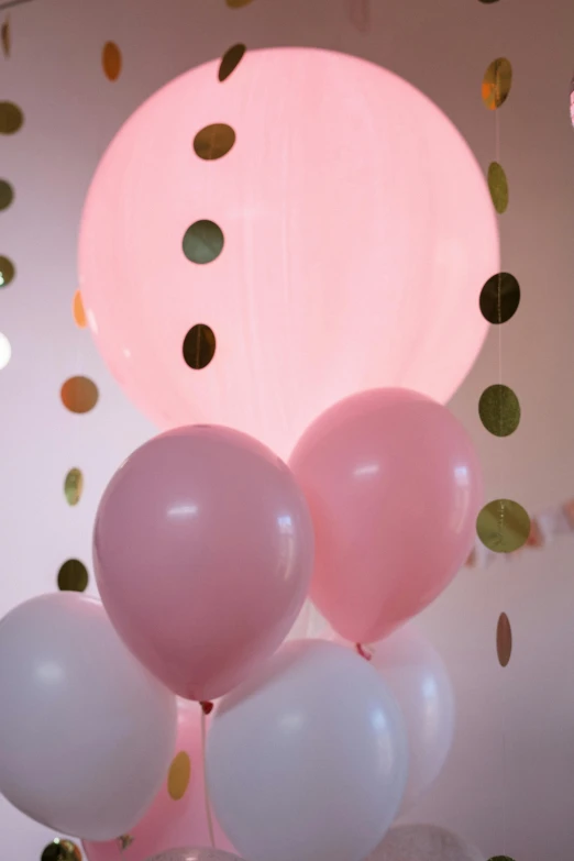 a bunch of balloons sitting on top of a table, pink light, pink and gold, varying dots, medium level shot