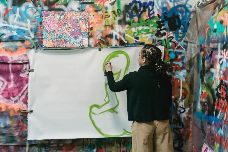 a man standing in front of a wall covered in graffiti, trending on unsplash, process art, stands at her easel, facing away, child drawing, marker art