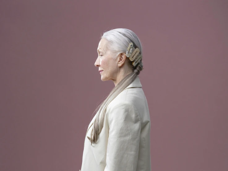 a woman standing in front of a pink wall, inspired by Anna Füssli, hyperrealism, silver hair (ponytail), hugh kretschmer, elderly, silver，ivory