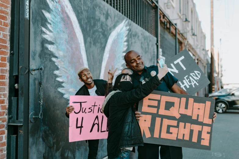 a couple of men standing next to each other holding signs, by Julia Pishtar, pexels contest winner, black arts movement, prideful, a person standing in front of a, celebrating, high quailty