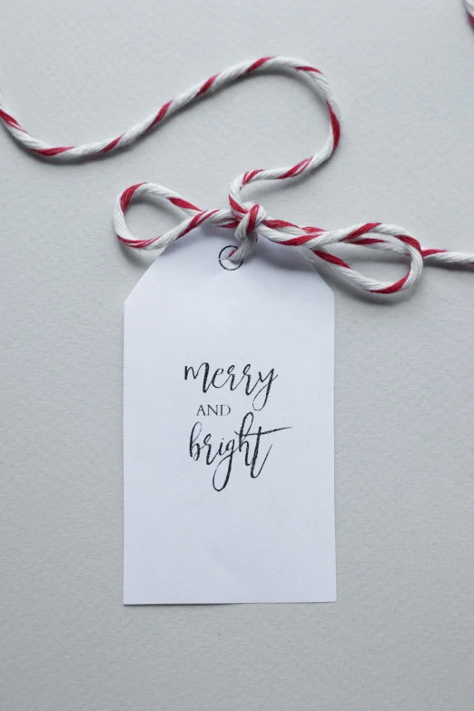 a christmas gift tag tied to a string, inspired by Henry Bright, crisp smooth clean lines, calligraphy, press photo, lighthearted