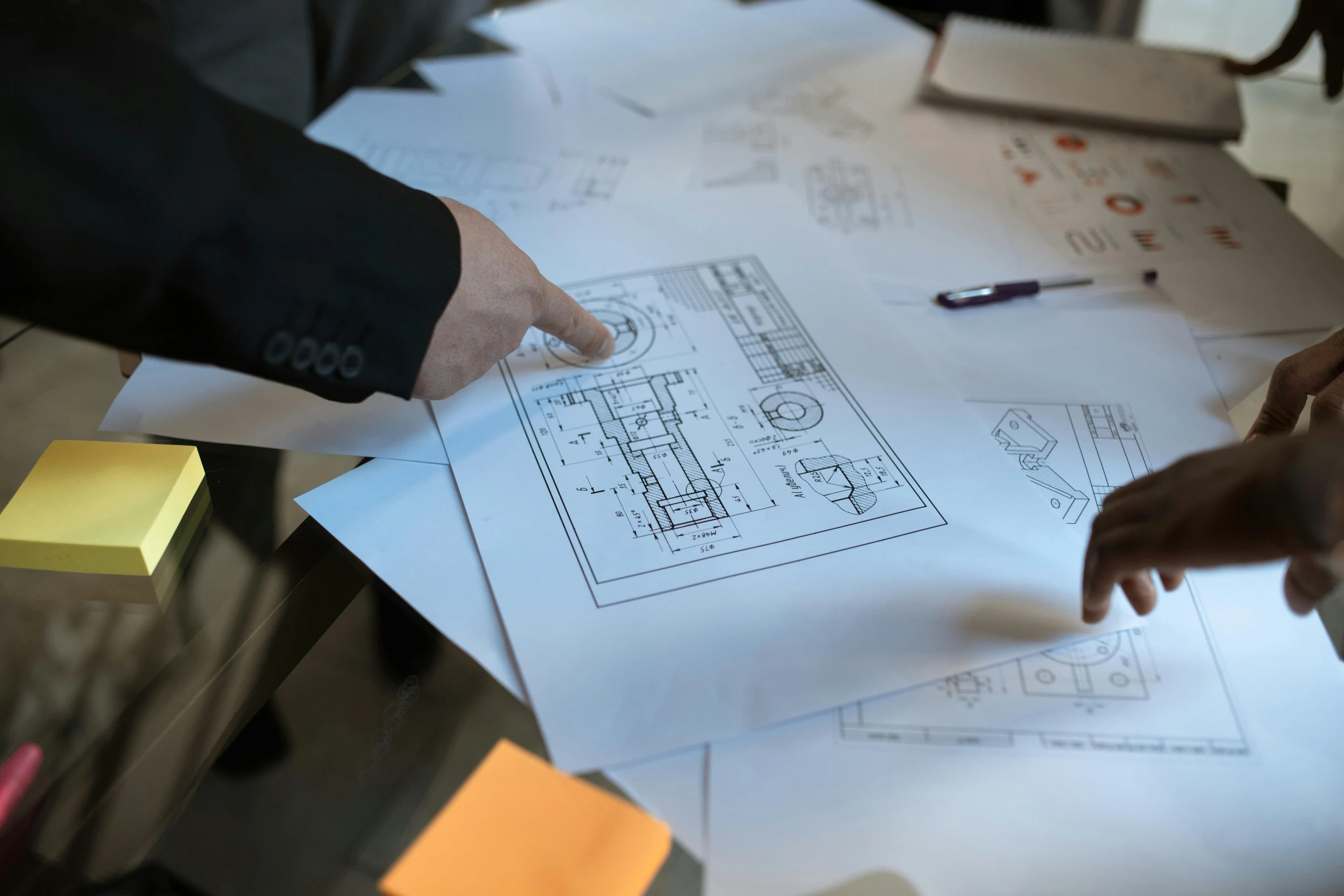 a group of people looking at blueprints on a table, a drawing, by Matt Cavotta, unsplash, with elements of the f40, on white paper, back of hand on the table, thumbnail