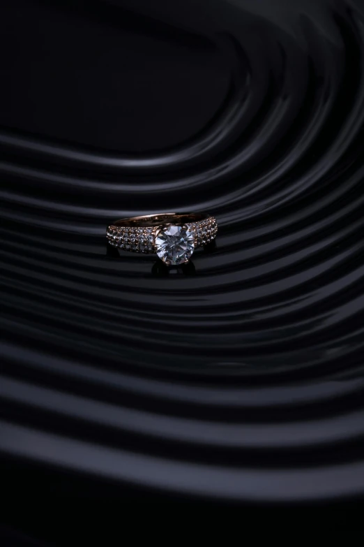 a ring sitting on top of a body of water, on a dark background