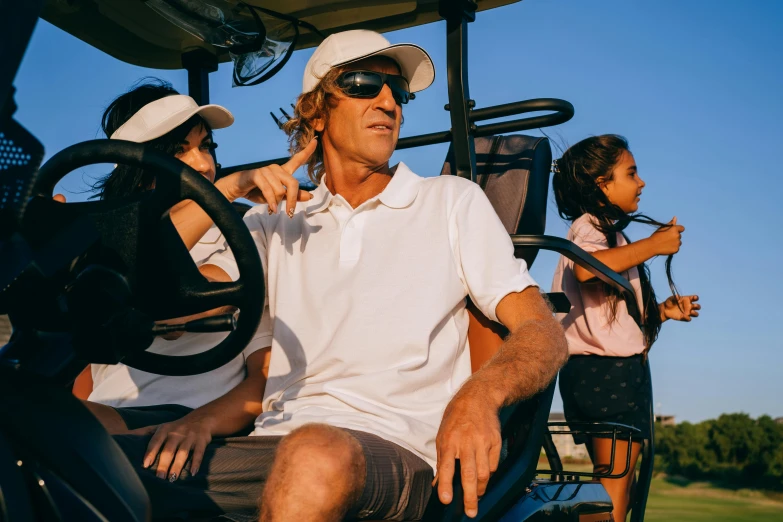 a man sitting in the driver's seat of a golf cart, pexels contest winner, happening, family, wearing sunglasses and a cap, avatar image, ground level shot