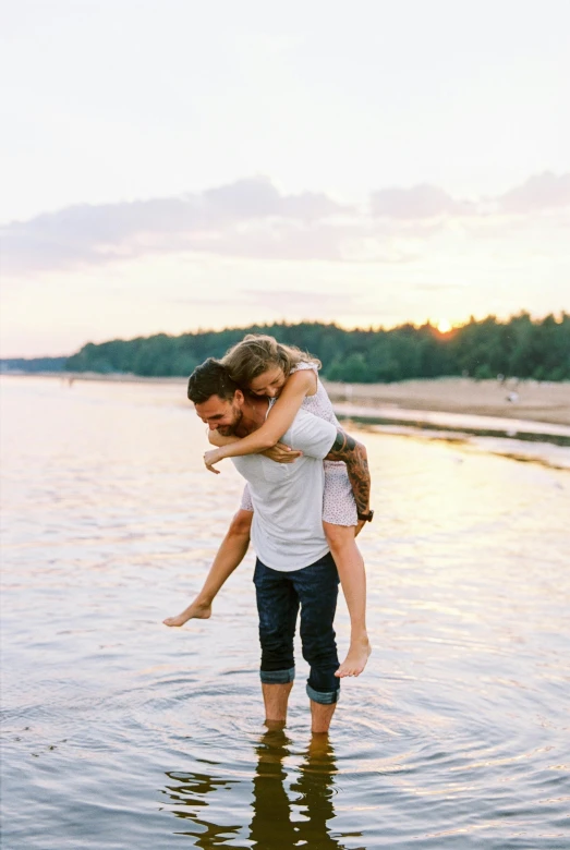 a man carrying a woman in a body of water, cute photograph, day setting, 2 people, outdoors