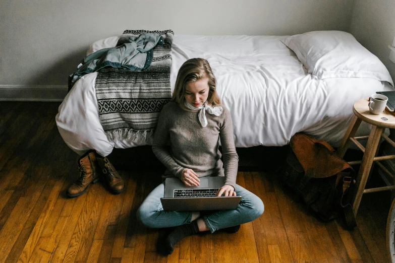 a woman sitting on the floor with a laptop, by Carey Morris, trending on unsplash, hotel room, small and cosy student bedroom, sydney sweeney, rectangle