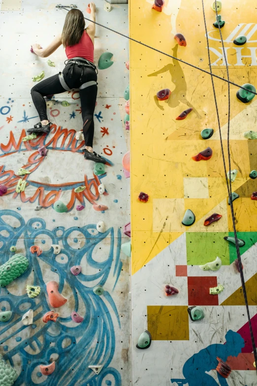 a woman climbing up the side of a rock wall, trending on pexels, process art, things hanging from ceiling, campy and colorful, sports photo, seen from above