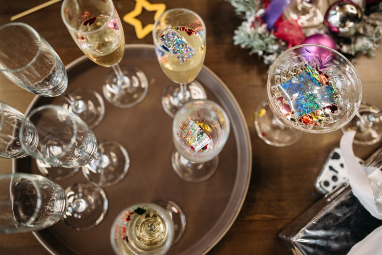 a bunch of wine glasses sitting on top of a table, by Julia Pishtar, covered in sprinkles and crumbs, festive, soap bubble, board games on a table