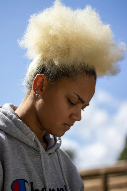 a close up of a person with a cell phone, by Washington Allston, short blonde afro, looks sad and solemn, with a ponytail, 2019 trending photo