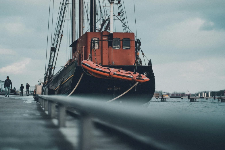 a boat sitting on top of a body of water, by Adam Marczyński, pexels contest winner, dark grey and orange colours, rugged ship captain, 🚿🗝📝, red and black colour scheme