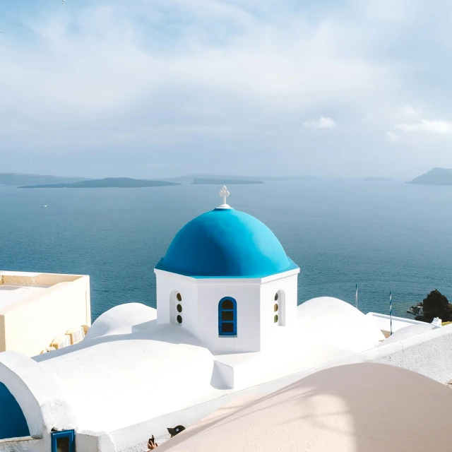 a blue dome sitting on top of a white building, by Carey Morris, pexels contest winner, hills and ocean, holy themed, slightly tanned, video