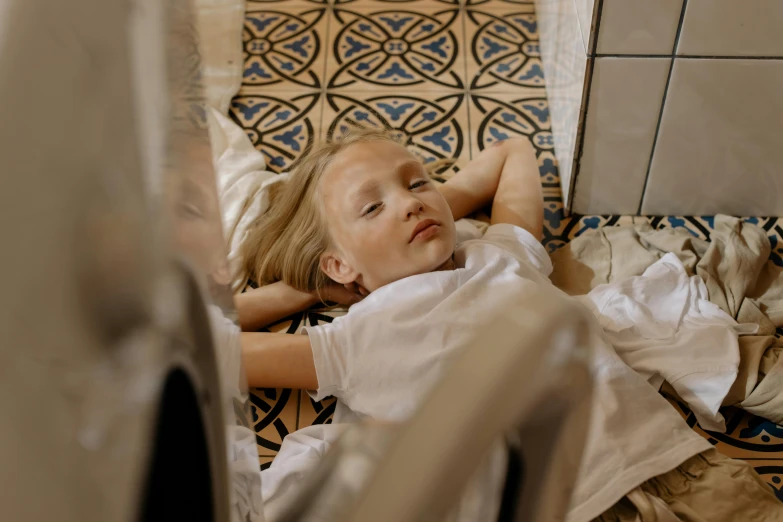 a little girl that is laying down on the floor, inspired by Sarah Lucas, pexels contest winner, tiles, bedhead, gif, decoration