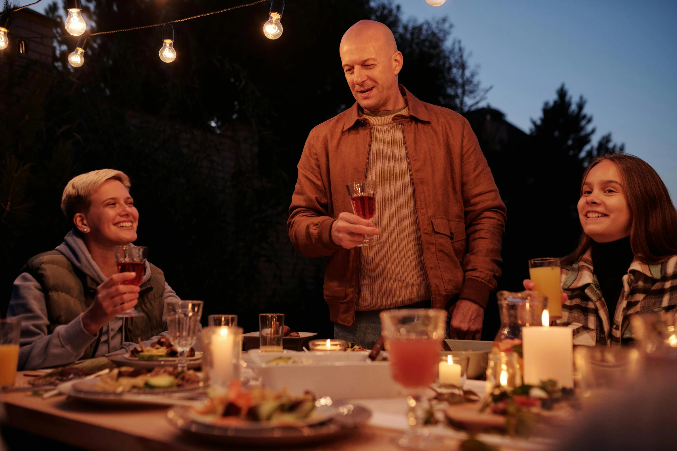 a group of people sitting around a dinner table, outdoor lighting, profile image, booze, gardening