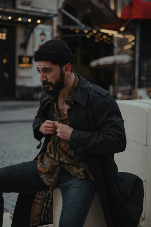 a man with a beard sitting on a wall, a portrait, by Micha Klein, pexels contest winner, vintage clothing, promo image, wearing jacket, paisley