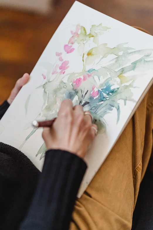 a woman is drawing flowers on a piece of paper, a watercolor painting, inspired by artist, trending on unsplash, large portrait, fine art print, on canvas