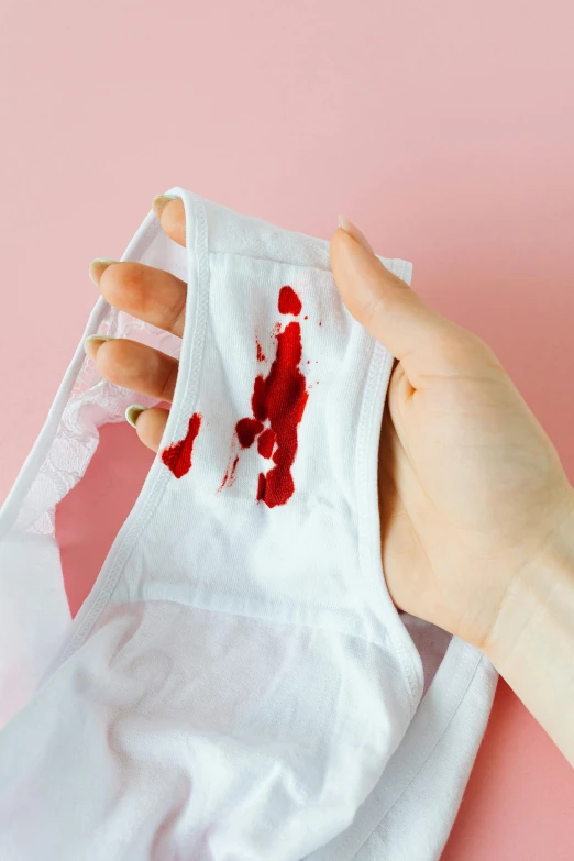 a person holding a piece of cloth with blood on it, by Julia Pishtar, wearing white camisole, product shot, stitches, puke