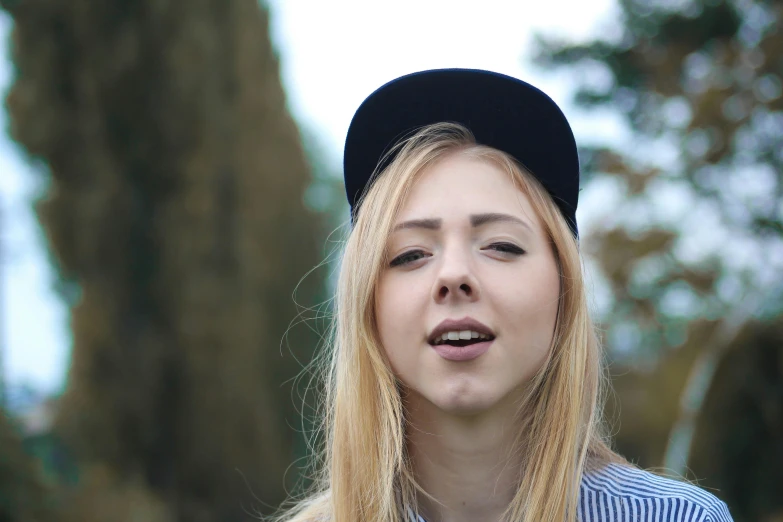 a close up of a person with a hat on, an album cover, by Julia Pishtar, unsplash, a girl with blonde hair, rapping, youtube video screenshot, in a park