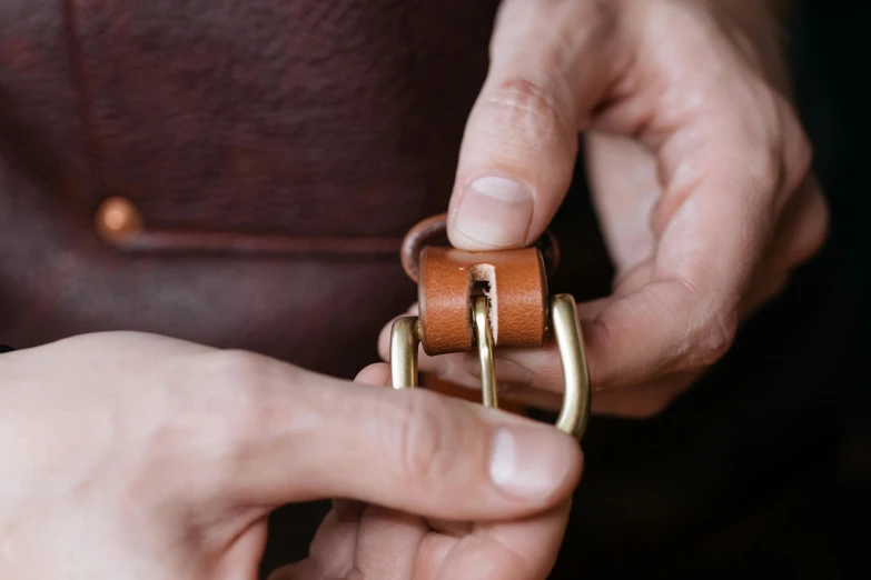 a close up of a person holding a ring, inspired by Henry Otto Wix, leather belt, assembly instructions, brown, metal handles