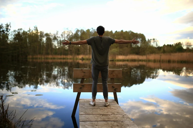 a man standing on a dock with his arms outstretched, pexels contest winner, sitting at a pond, friendship, looking out, screensaver