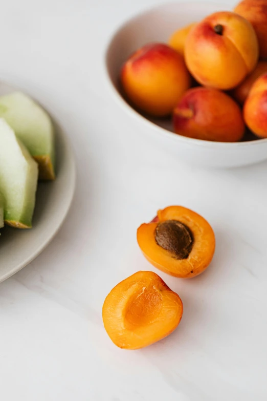 a white plate topped with sliced fruit next to a bowl of peaches, unsplash, epicurious, thumbnail, snacks, half image