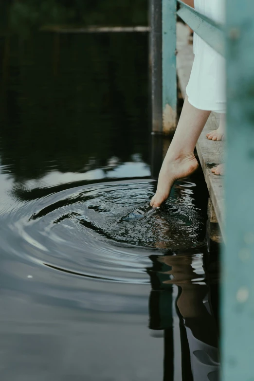 a person standing on a dock next to a body of water, happening, very close up foot shot, swirling around, ignant, bath