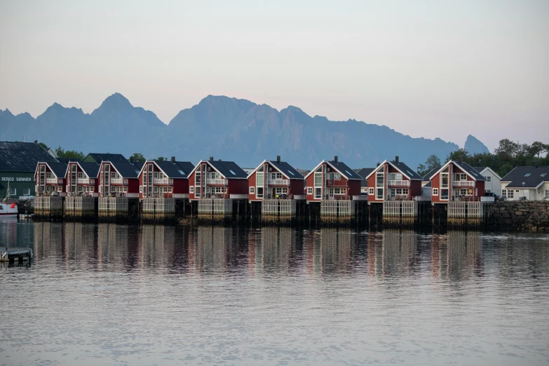 a row of houses sitting on top of a body of water, by Constantin Hansen, pexels contest winner, scandinavian / norse influenced, avatar image, late summer evening, huts