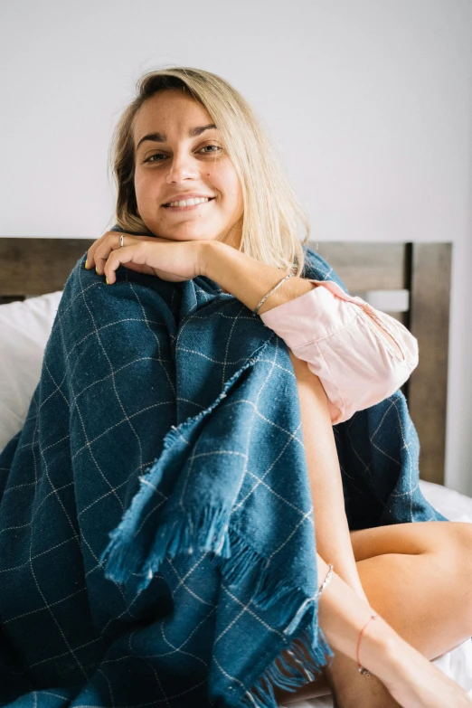 a woman sitting on top of a bed covered in a blanket, full product shot, navy, teal cloth, sydney sweeney