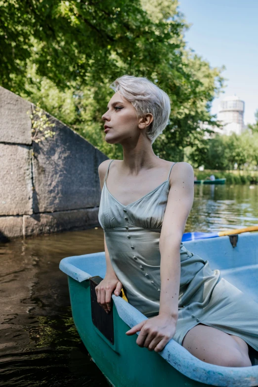 a woman in a dress is sitting in a boat, an album cover, inspired by Elsa Bleda, trending on unsplash, short platinum hair tomboy, in a city park, angelina stroganova, pearlescent skin