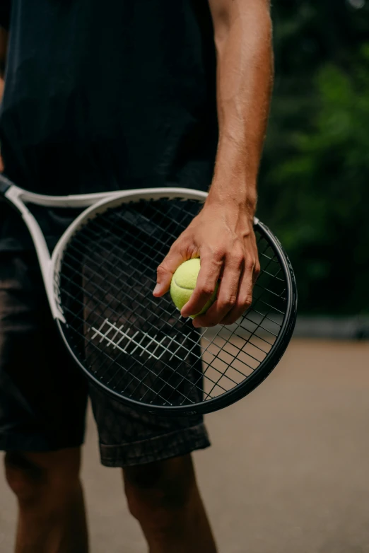 a man holding a tennis racket and a tennis ball, zoomed out