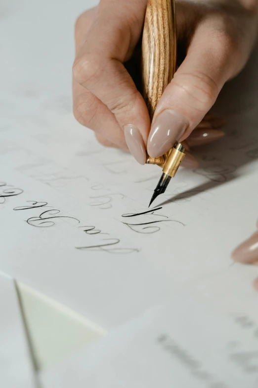 a person writing on a piece of paper with a pen, “modern calligraphy art, golden detailing, thumbnail, on a canva