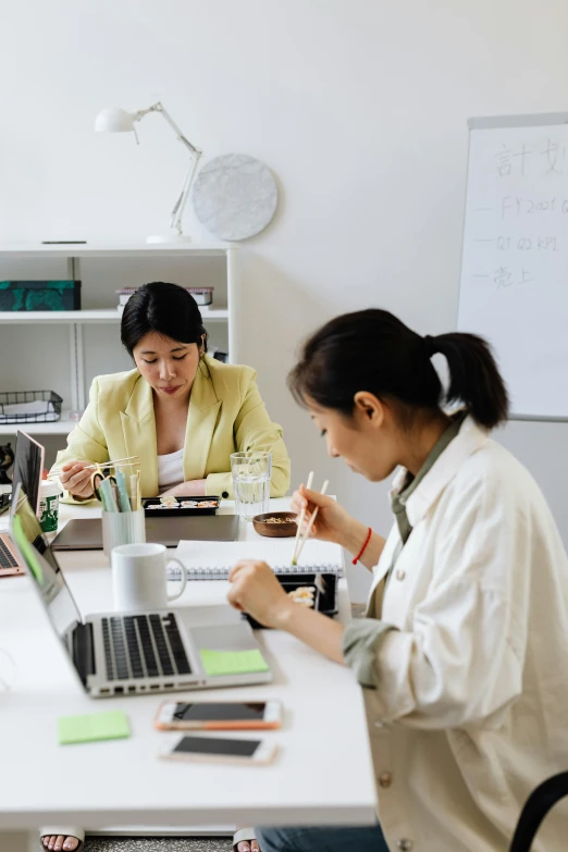 a group of people sitting at a table with laptops, by Jang Seung-eop, trending on pexels, arbeitsrat für kunst, two women, ethnicity : japanese, set inside of office, slightly minimal