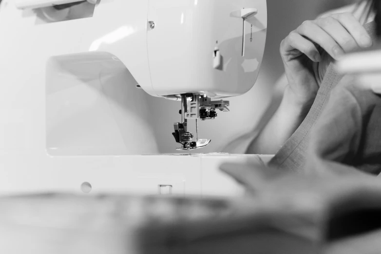 a woman is working on a sewing machine, a black and white photo, by Matija Jama, pexels, process art, made of fabric, white, multi-part, designer product