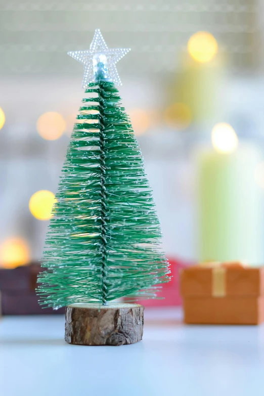 a small christmas tree sitting on top of a table, a tilt shift photo, by Helen Stevenson, pexels, process art, detailed product image, detailed acrylic, a wooden, green sparkles