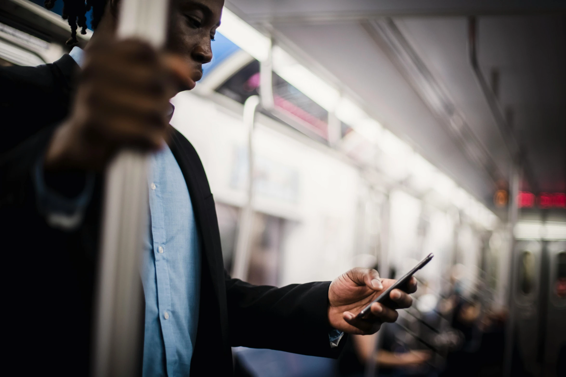 a man on a subway looking at his cell phone, by Carey Morris, trending on unsplash, fan favorite, black man, elegantly dressed, thumbnail