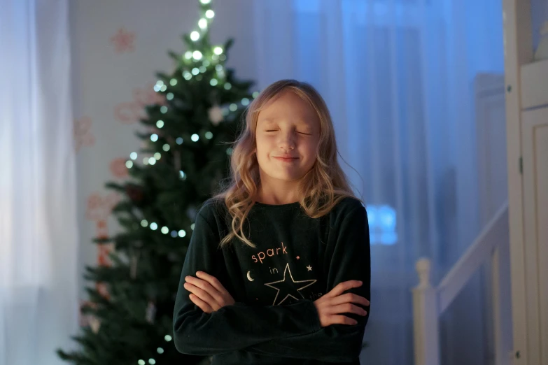 a little girl standing in front of a christmas tree, a cartoon, pexels, wearing sweatshirt, low - light photograph, (winking), starry