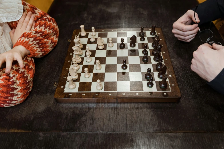 a group of people playing a game of chess, by Daniel Lieske, pexels contest winner, on wooden table, white finish, sitting on a mocha-colored table, female gigachad