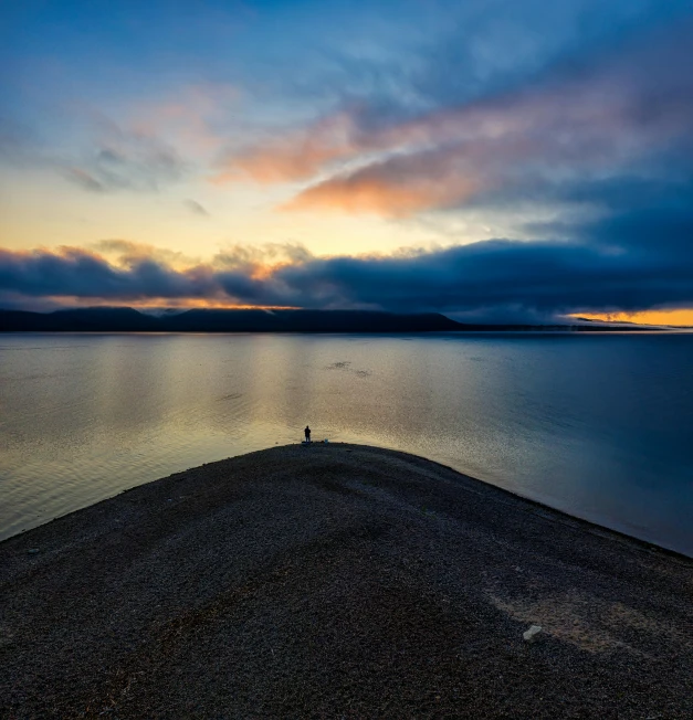 a lone person standing on the edge of a large body of water, by Hallsteinn Sigurðsson, pexels contest winner, 8k hdr dusk light, bird eye view, 2 people, with dramatic sky