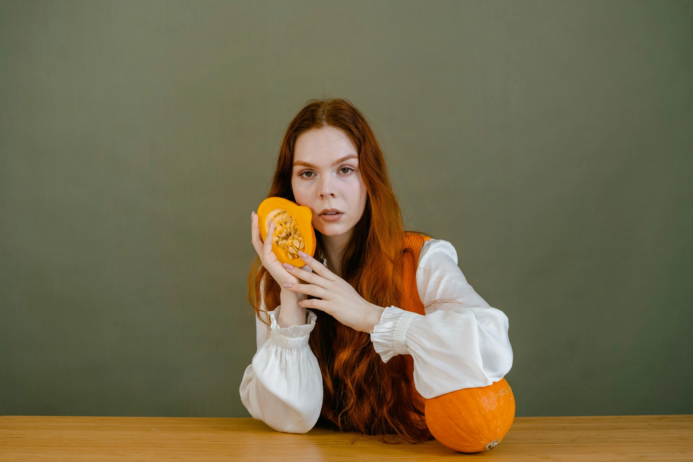 a woman sitting at a table holding a donut, inspired by Elsa Bleda, pexels contest winner, magic realism, holding a jack - o - lantern, medium long wavy ginger hair, portrait anya taylor-joy, 15081959 21121991 01012000 4k